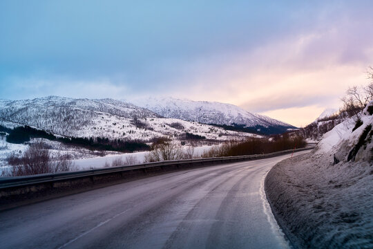 POV driving on curved wet asphalt road during winter road trip in Lofoten Norway