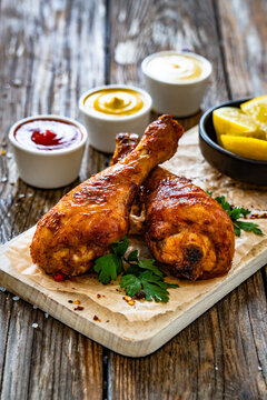 Air fryer chicken drumsticks with mayonnaise, ketchup and mustard on wooden table
