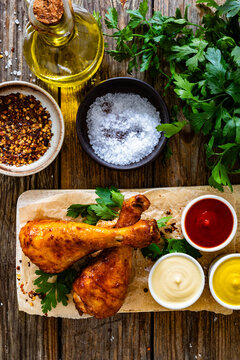 Air fryer chicken drumsticks with mayonnaise, ketchup and mustard on wooden table. Top view

