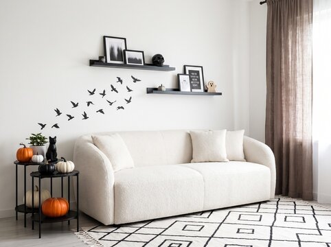 Cozy living room interior with a white sofa floating shelves and decorative bird wall decals for a modern home