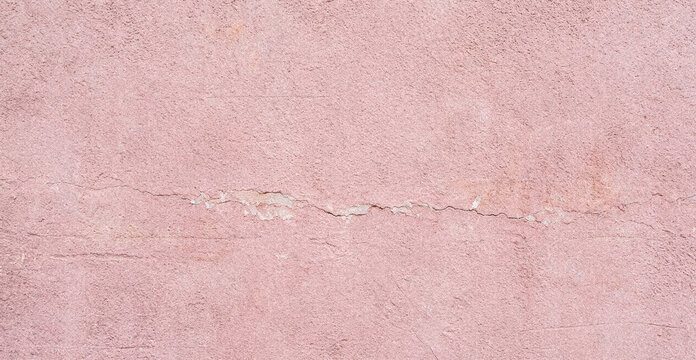A close-up view of a textured pink wall, showcasing subtle variations in color and a faint horizontal crack running across the surface.
