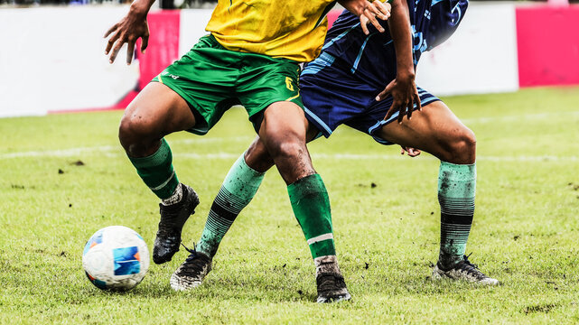 Intense football tackle as two soccer players battle for ball po