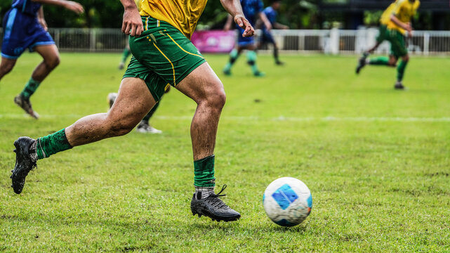 Close-up of soccer athlete running with the ball on grass field in football competition