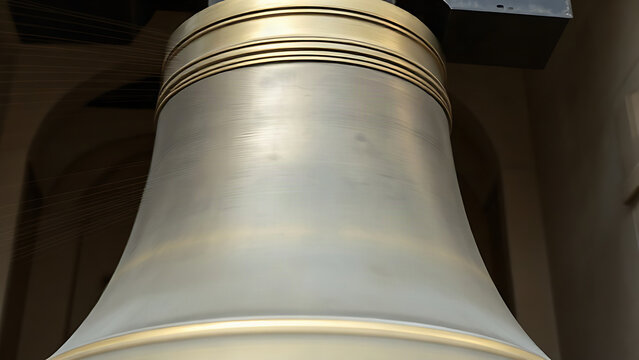 A large bronze church bell in motion with subtle air distortion around it.