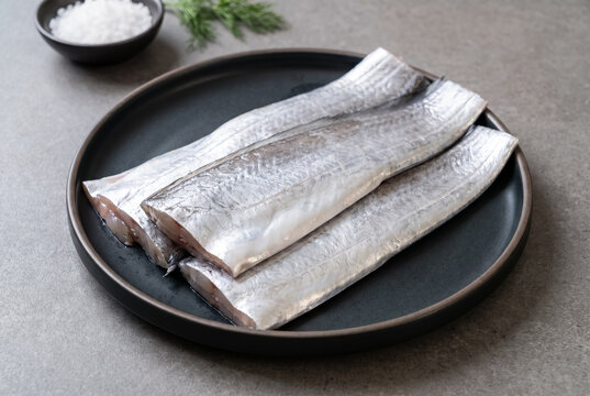 Fresh Raw Hairtail Fillets on Dark Plate