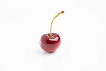 Single ripe cherry with long stem on white background, minimalist fruit photography highlighting color and texture © P10NERO