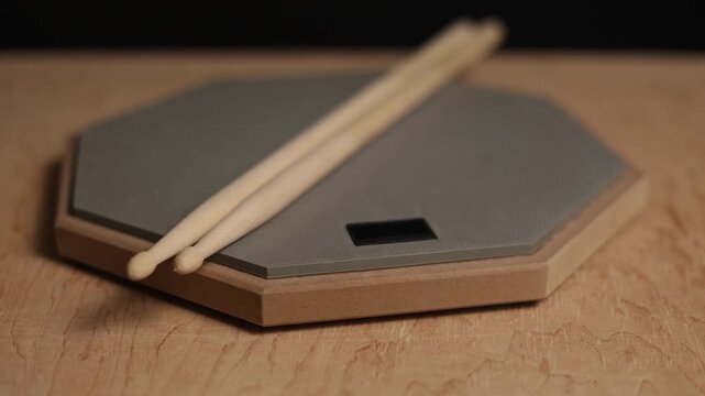 Drum practice pad with sticks resting on a wooden surface