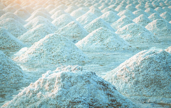 Sea salt piles in traditional salt farm during solar evaporation process for natural sodium chloride production and sustainable mineral harvesting in Thailand. Organic sea salt crystallization.