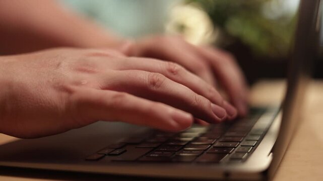 Close-up of hands typing on a laptop keyboard, focused on digital work