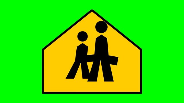 Road sign displaying a black silhouette of children walking against a yellow pentagonal background warns motorists of an upcoming school zone on a bright green field.