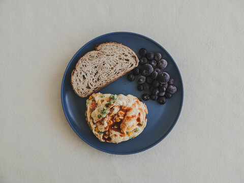 Overhead view of a balanced meal: vegetable omelet, whole grain bread, frozen blueberries.
