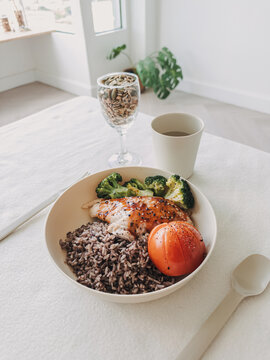 Balanced and healthy homemade meal with grilled chicken, black rice, broccoli, and fresh tomato.