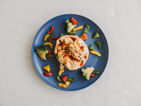 Savory egg rolls with fresh broccoli and colorful bell peppers served on a blue plate.
