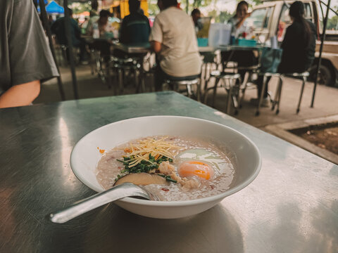 Asian rice porridge with soft-boiled egg and ginger, served at a casual street stall
