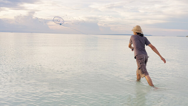 a fisherman in indonesia throwing or casting a fishing net in ocean, indonesian people, southeast asia