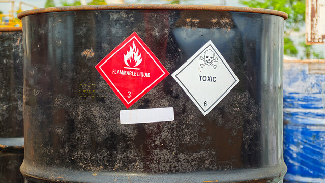 Toxic chemical with skull icon and flammable liquid warning sign on hazard chemical metal barrel. Industrial safety sign, close-up with selective focus