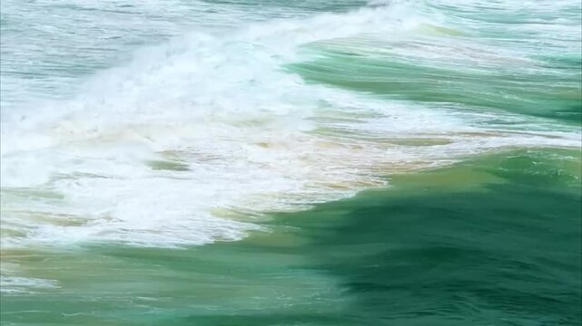 Turquoise Emerald Ocean Waves Crashing with White Foam and Sand Mix in Sea Water