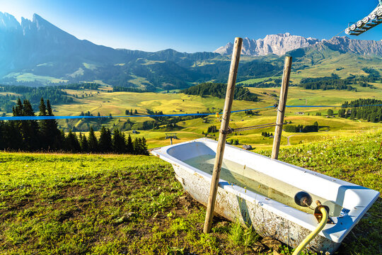 Bathtub cattle trough on hill above Seiser Alm pastures scenic landscape. Alpe di Siusi.