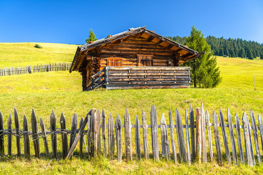 Alpine hut on green meadow of Seiser Alm heights view. Alpe di Siusi.