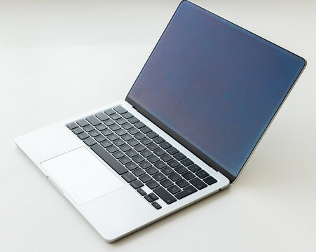 Modern silver laptop computer open on white surface studio shot