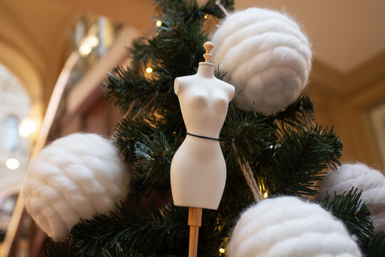 fashion themed christmas decor featuring a small mannequin dress form on fir branches,paired with oversized fluffy wool balls and warm fairy lights in an indoor holiday display