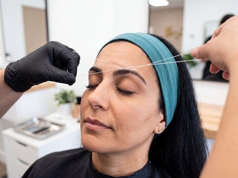 woman eyebrow threading beauty salon hair removal cosmetic treatment professional rests with closed eyes while a technician shapes her brows for grooming precision spa service and beauty advertising