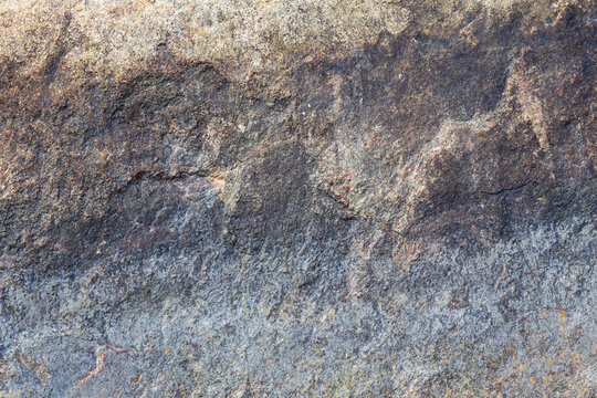Close-up of coarse gray rock reveals intricate natural patterns and uneven surface.