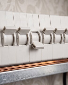 Close-up row of white residential miniature circuit breakers on a DIN rail with one switch turned off