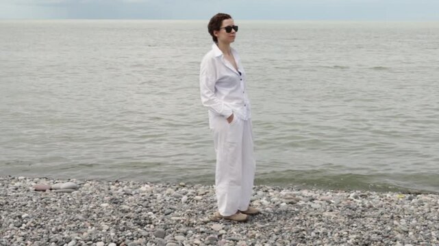 cancer survivor in light protective clothing stands by the sea during a wellness holiday, enjoying a calm beach break while practicing sun safety and recovery self care