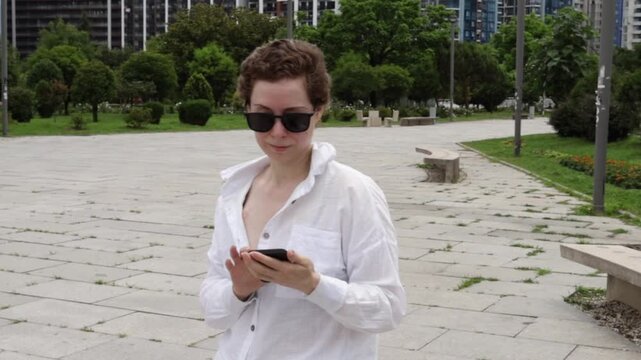 middle aged woman checks a mobile health app in a public park, representing telehealth, treatment follow up and technology supported cancer survivorship