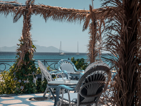 Greek taverna table and chairs overlooking anchorage with yachts and mountains