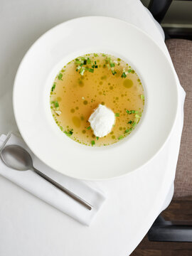 Clear broth with herbs and dollop of cream, fine dining experience, upscale restaurant menu