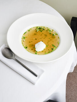 Broth with herb oil and dollop of whipped cream, upscale dining experience, gourmet cuisine concept