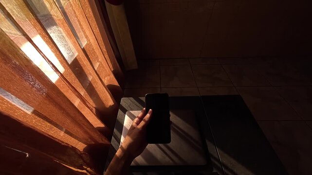 A relaxing landscape video showing someone browsing or scrolling on their mobile phone while casually taking a sip of a drink. The phone screen is completely black, offering a perfect green-screen-lik