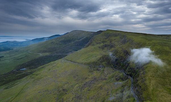 Drone aerial scenery view Winding road green valley coastline and ocean in the distance. Connor Pass Dingle Peninsula Ireland. Irish landscape