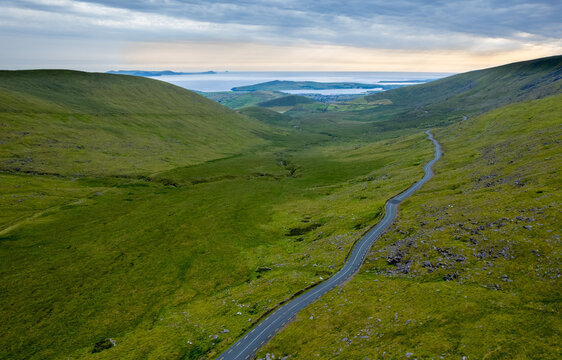 Drone aerial scenery view Winding road green valley coastline and ocean in the distance. Connor Pass Dingle Peninsula Ireland. Irish landscape