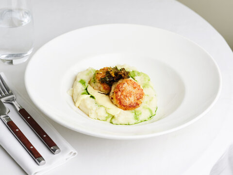 Crispy turkey patties on creamy mashed potatoes with green herb sauce, fine dining experience, upscale restaurant menu