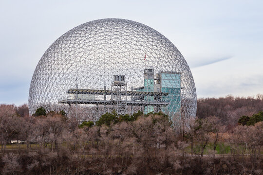 St. Helen's Island, Montreal, Quebec, Canada, November 26, 2025 - The famous geodesic dome, the 1967 Biosphere - now an interpretative environment museum - seen nestled in bare trees during grey fall 