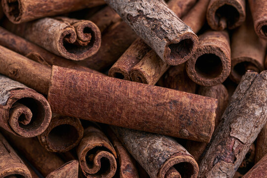 Close-up pile of aromatic raw cinnamon sticks spice background