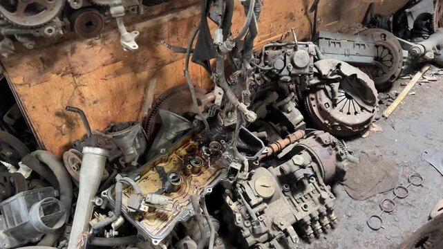 Atmosphere of salvage auto parts shop in Indonesia, the racks are filled with engines, shaft, and other spare parts. The condition is quite dirty and dark
