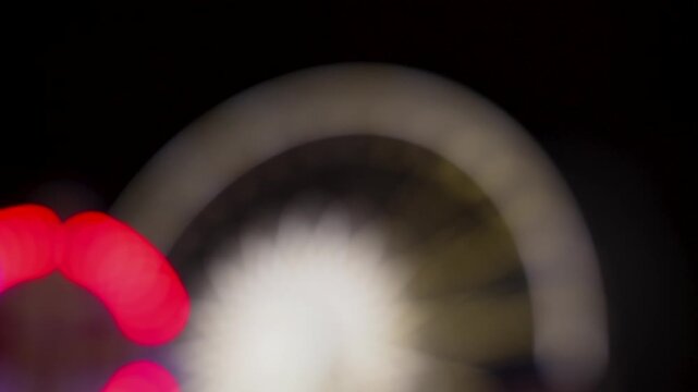abstract lights of a ferris wheel and carnival rides at night
