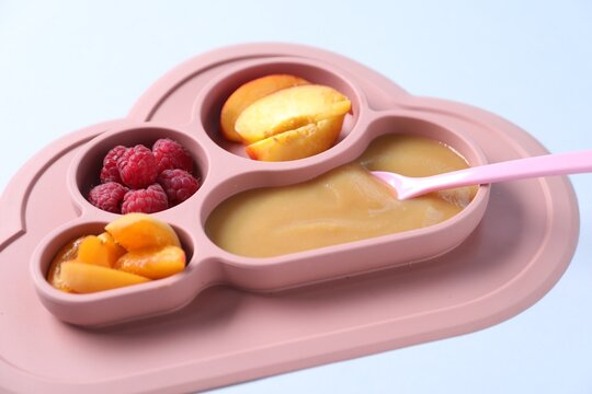 Baby tableware. Section plate with food on white background, closeup