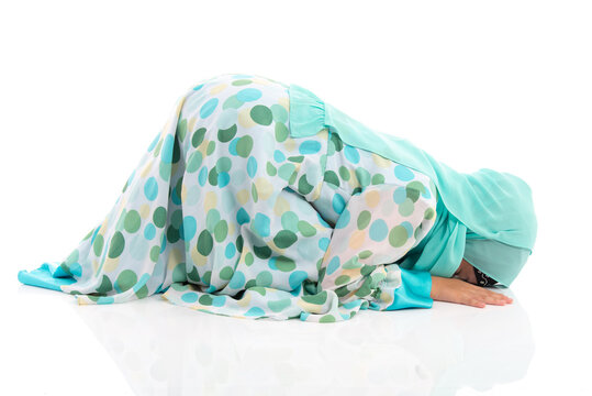 Side view horizontal portrait of cute young Asian Muslim girl performing Sujud prostration isolated on white background.