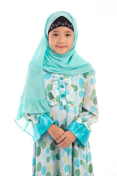 Charming young Muslim girl with hijab posing politely with hands clasped isolated on white background.