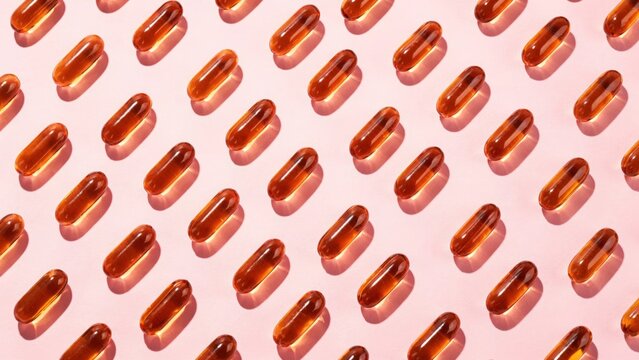 Seamless pattern of brown gelatin capsules arranged diagonally on a soft pink background with capsules, supplement
