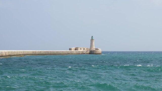 stone causeway stretches to a lighthouse marking valletta harbour mouth open mediterranean water surrounding valletta breakwater st elmo breakwater harbour entrance lighthouse tower arched bridge