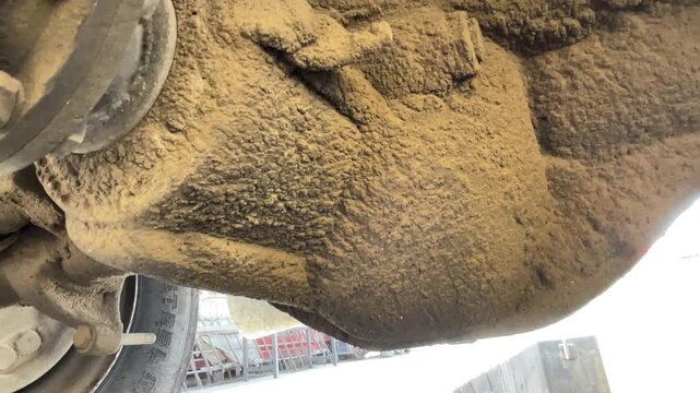 Closer view of a dusty truck suspension joint and axle hardware, showing heavy grime, bolts, metal surfaces, and mechanical wear during an outdoor heavy-vehicle inspection in daylight today.