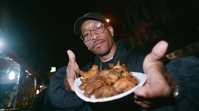 Young Man Presenting Fresh Street Food at Night Market
