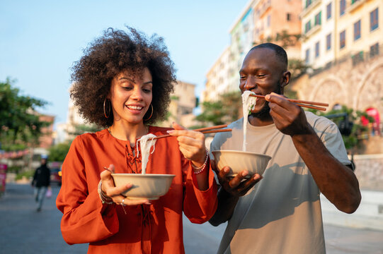 Diverse young friends enjoying street food together, sharing a happy, authentic multicultural moment
