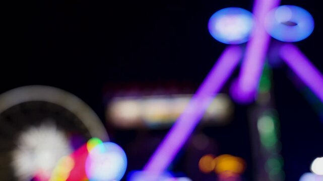 Wide shot of soft focus colorful carnival rides at the fair